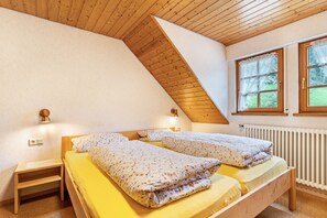 A bedroom with two beds, a sloped ceiling, a window with a view, and a radiator. - Apartment 3 in Farmhouse with Shared Terrace, Garden, and Wi-Fi (Bad Rippoldsau-Schapbach)