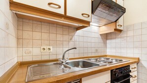 Une cuisine équipée d’un évier à deux bacs, d’appareils électroménagers en acier inoxydable, de meubles en bois et d’un four encastré.