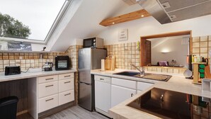 Una cocina moderna con tragaluz, electrodomésticos de acero inoxidable y techo de madera.