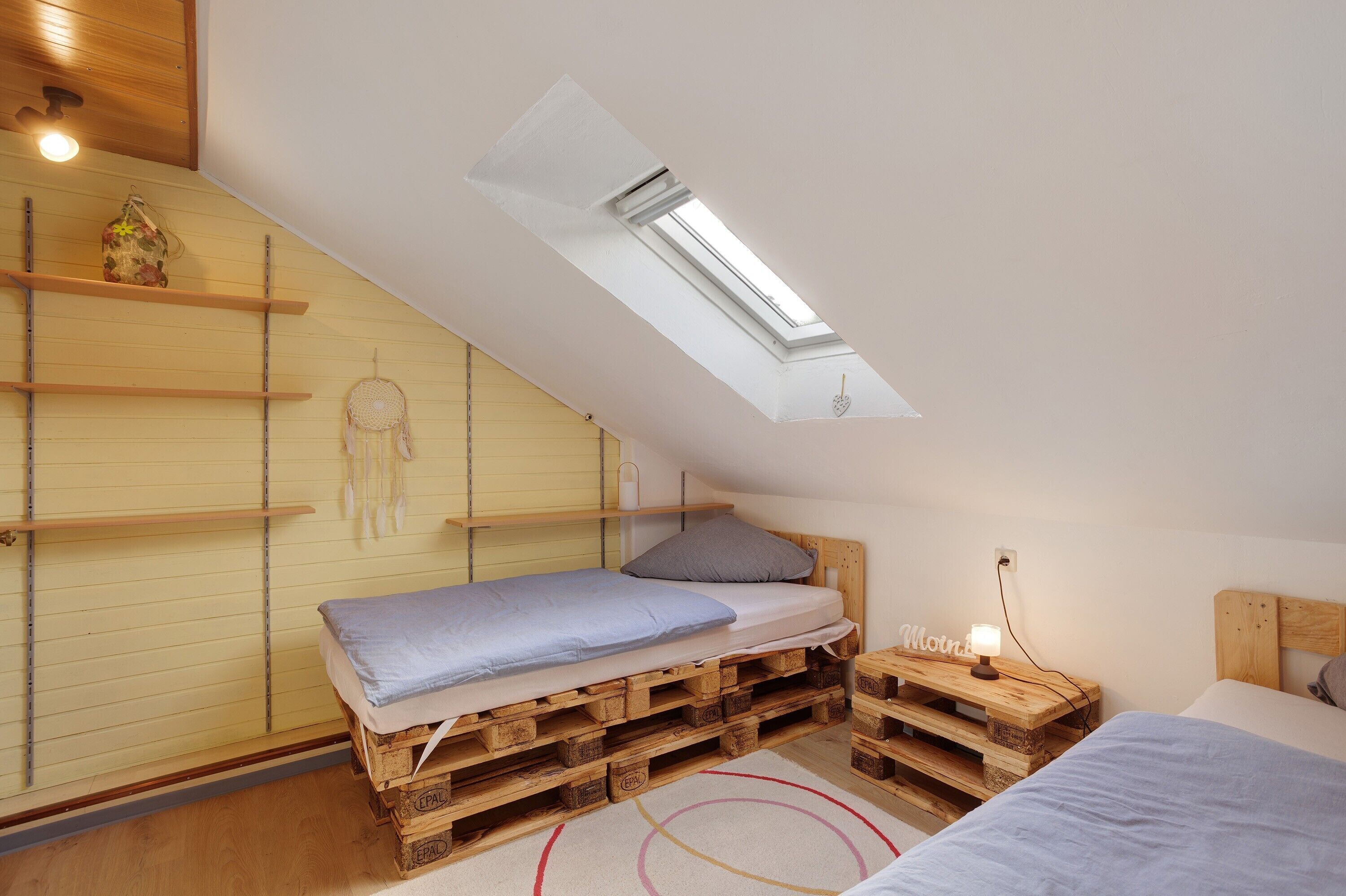 Ein Schlafzimmer im Loft-Stil mit Dachfenster, Holzböden und einem Bett mit Kopfteil.