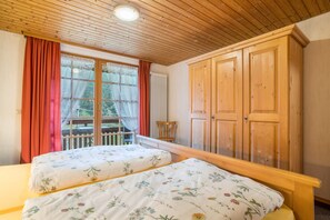 Un dormitorio con dos camas, un armario de madera y una ventana con cortinas.
