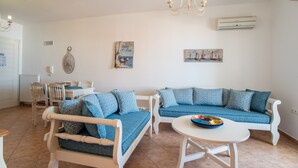 Un soggiorno con un divano bianco, un divano blu, un tavolo da pranzo e un lampadario.