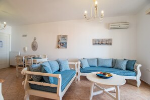 Un salon avec un canapé blanc, un canapé bleu, une table à manger et un lustre.