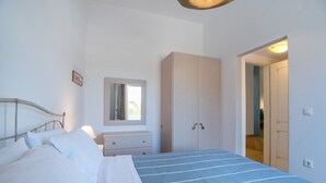 Een slaapkamer met een bed, een dressoir, een kledingkast en een spiegel.