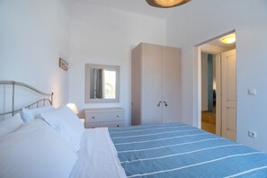 A bedroom with a bed, a dresser, a wardrobe, and a mirror.