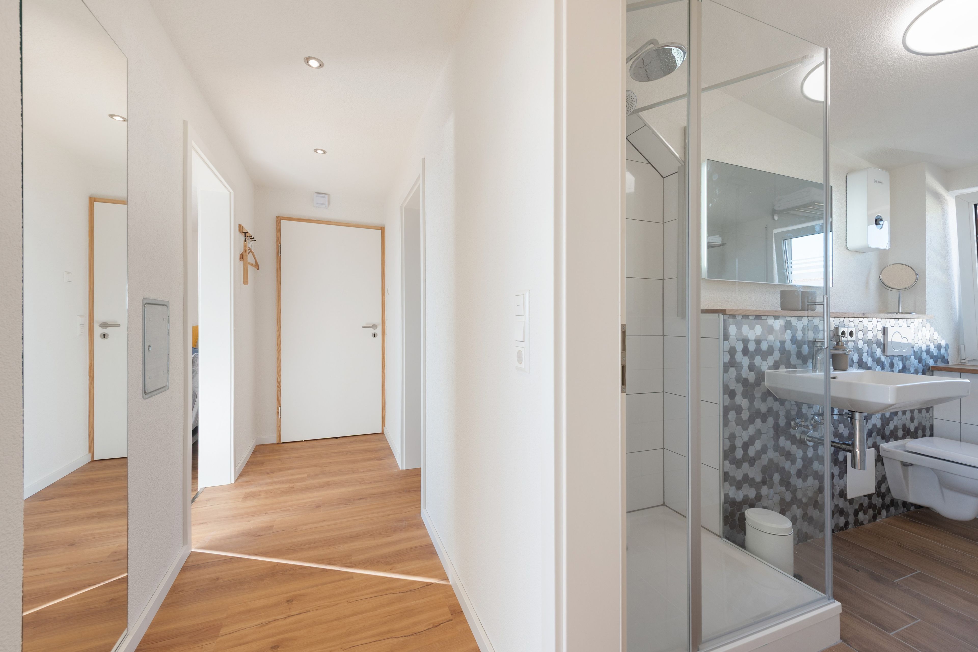 Une salle de bain moderne avec une douche à parois de verre, un lavabo blanc et un mur recouvert de carreaux.