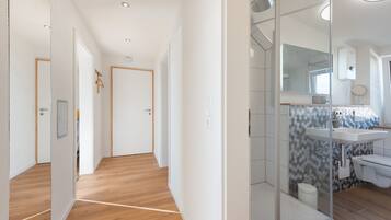 Une salle de bain moderne avec une douche à parois de verre, un lavabo blanc et un mur recouvert de carreaux.