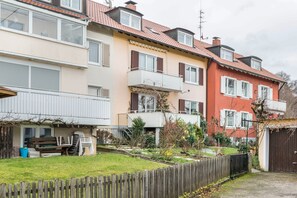Une rangée d’immeubles résidentiels dotés de balcons, d’une clôture en bois et d’un espace jardin.