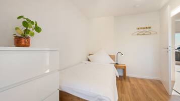 Une chambre à coucher avec un lit, une table de chevet, une lampe et une plante.