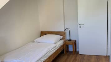 Ein Schlafzimmer mit einem hölzernen Bett, einem Nachttisch, einer Lampe und einer weißen Tür.