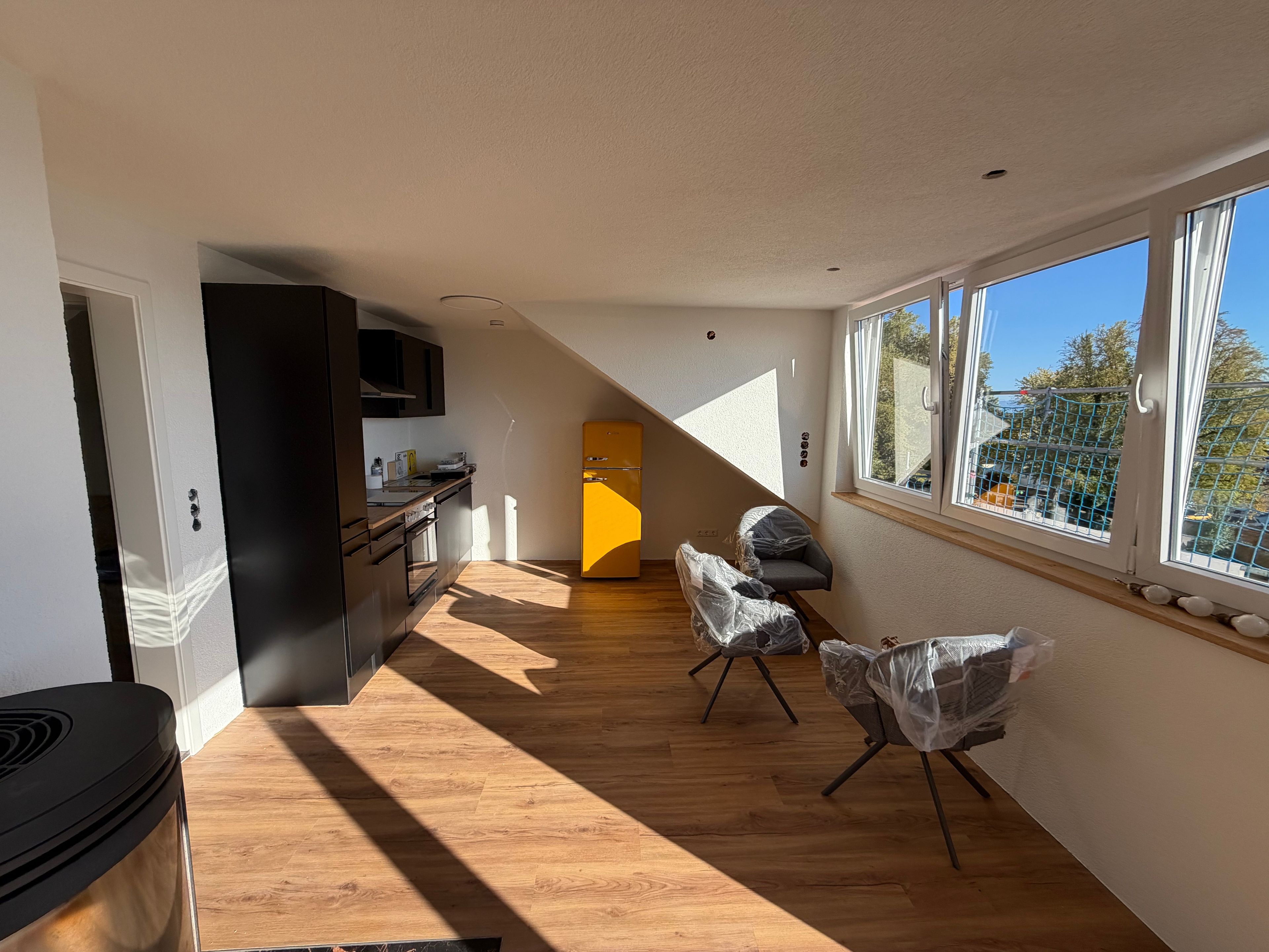 Une cuisine moderne avec un plancher en bois, un réfrigérateur jaune et un coin repas avec des chaises.