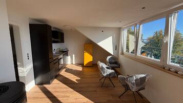 Une cuisine moderne avec un plancher en bois, un réfrigérateur jaune et un coin repas avec des chaises.