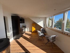 Una cocina moderna con piso de madera, un refrigerador amarillo y un comedor con sillas.
