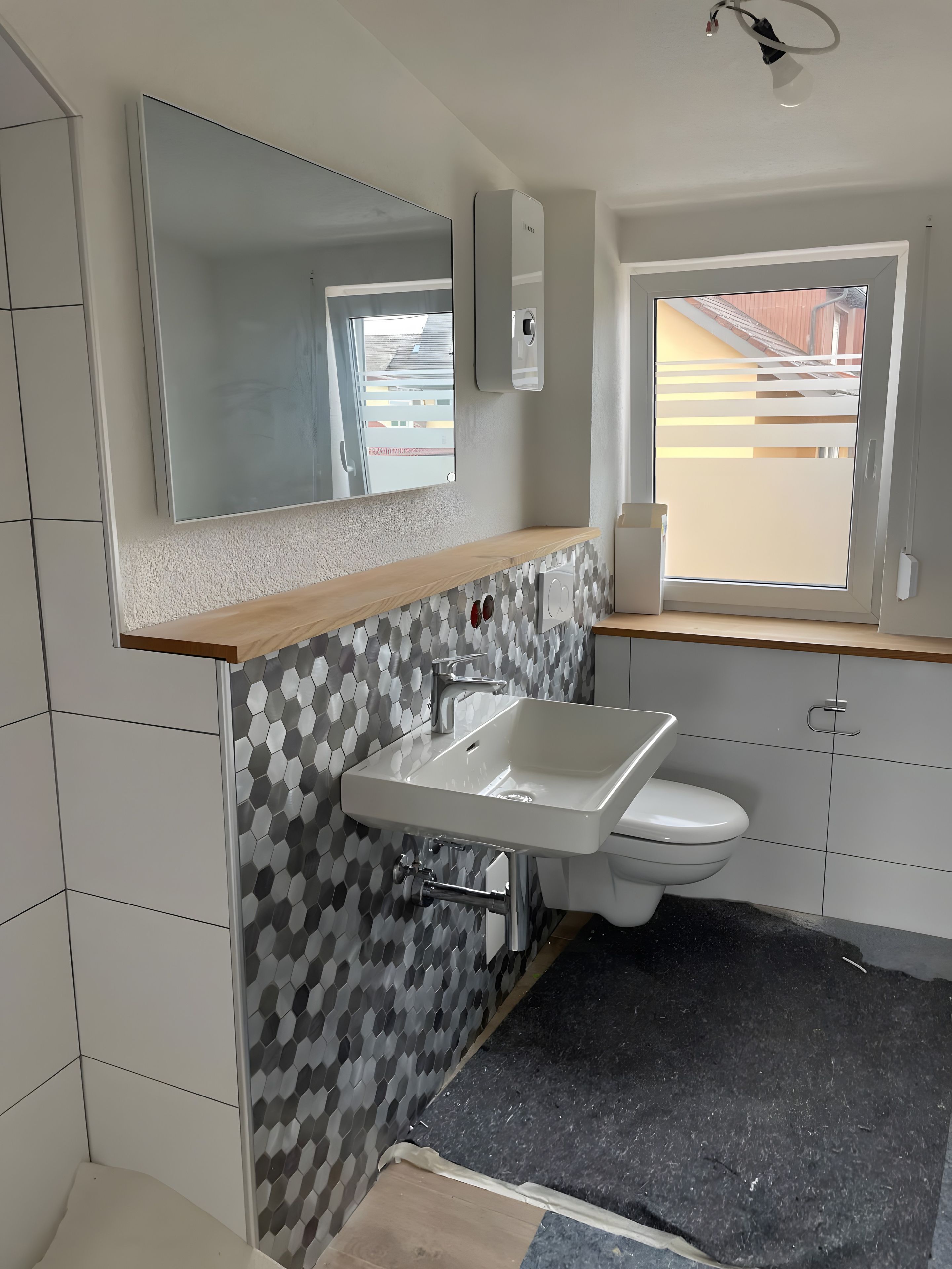 Een badkamer met een wit wastafelmeubel, een spiegel en een raam.