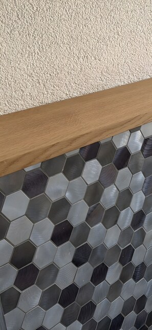 Un mur à texture, agrémenté d’une bordure en bois et recouvert d’un carrelage hexagonal.