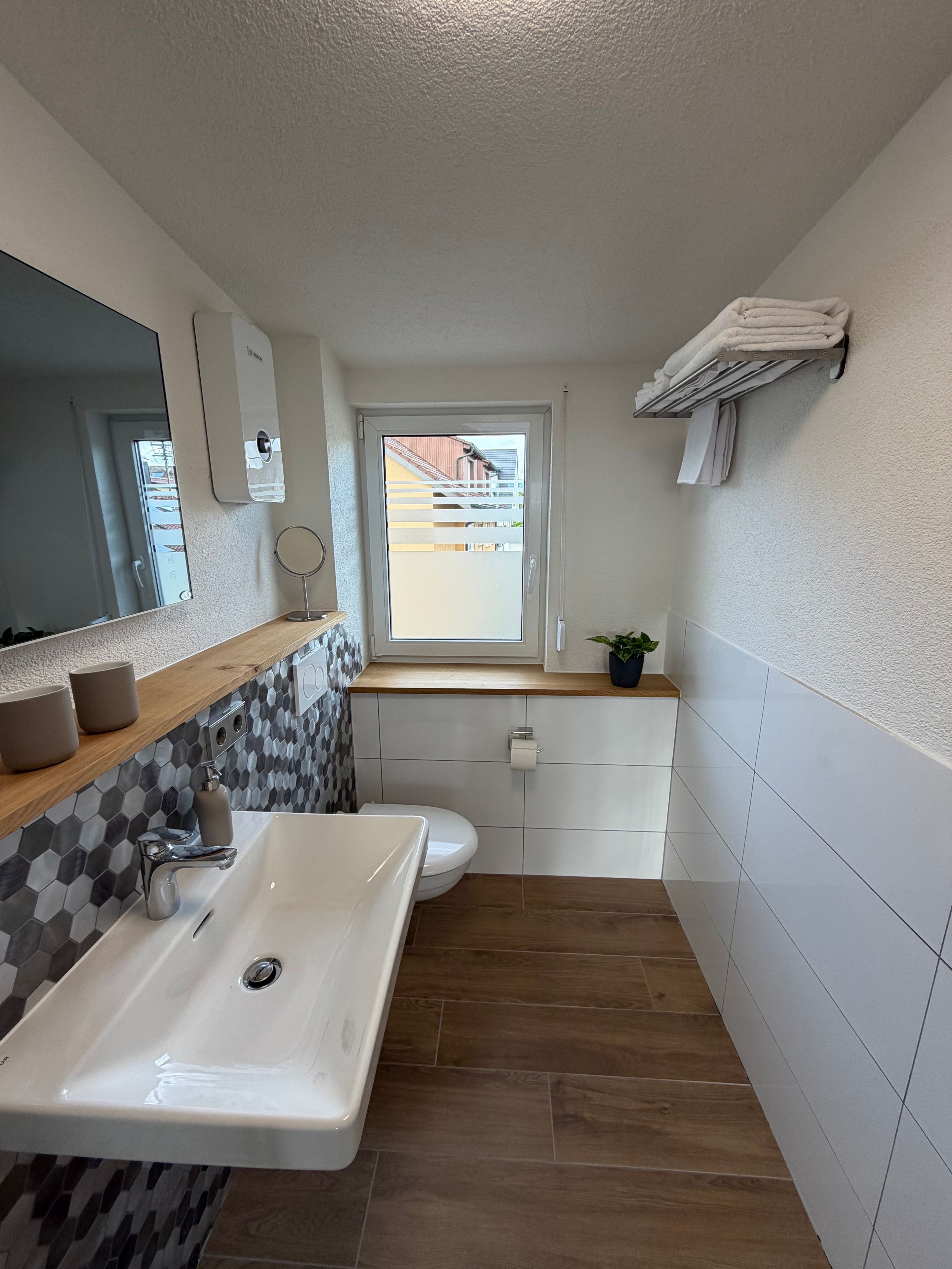 Ein kleines Badezimmer mit Waschbecken, Toilette und Fenster.