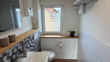 Ein kleines Badezimmer mit Waschbecken, Toilette und Fenster.