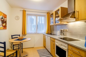 Una cocina compacta con comedor, un reloj y una ventana con cortinas.