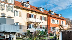 Eine Reihe von Wohngebäuden mit Balkonen, einem Gartenbereich und einem Holzzaun.