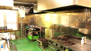 A commercial kitchen with stainless steel appliances, a ventilation system, and various kitchen utensils and containers. - LivingAnywhere CommonsAIZU-BANDAI (Bandai)