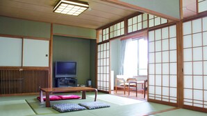 A traditional Japanese room with tatami flooring, a television, a low table, and sliding doors. - LivingAnywhere CommonsAIZU-BANDAI (Bandai)