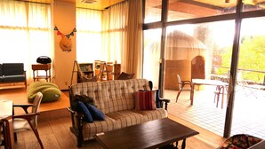 A cozy living room with a sofa, chairs, a coffee table, and a hammock. - LivingAnywhere CommonsAIZU-BANDAI (Bandai)