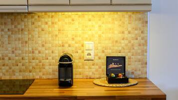 A kitchen with a tiled backsplash, a coffee machine, and a Nespresso coffee maker on the counter.