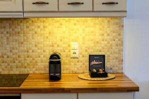 A kitchen with a tiled backsplash, a coffee machine, and a Nespresso coffee maker on the counter.