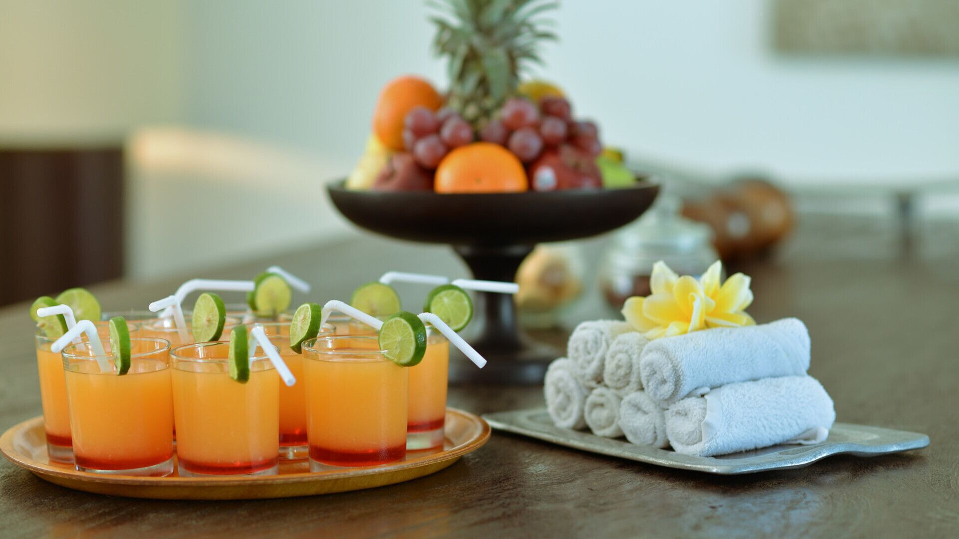 Une table avec des boissons, un panier de fruits et des serviettes.