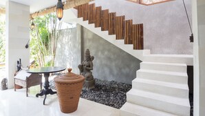 Un escalier au design moderne, une statue, une table et une lampe décorative.