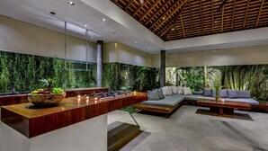 A modern interior with a wooden ceiling, a kitchen area with a fruit bowl, and a seating area with a sofa and cushions. - Beautiful Villa with Private Pool & Sunny Environment, Bali Villa 2138 (Bali)