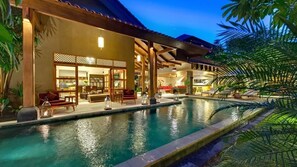 A poolside area with a covered seating area, a pool, and a building with traditional architectural elements.