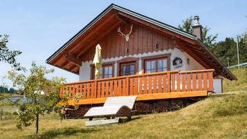 A wooden chalet with a balcony, a chimney, and a deer head decoration.