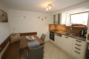 A compact kitchen with a dining area, wooden cabinets, a sink, and a window with a view. - Apartment 'Ferienwohnung Kasimir Hof' with Mountain View, Shared Garden and Wi-Fi (Seebach)