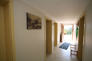 A hallway with a framed historical photo, a blue mat, and a wooden chair. - Apartment 'Ferienwohnung Kasimir Hof' with Mountain View, Shared Garden and Wi-Fi (Seebach)