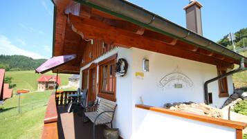 Ein Holzgebäude mit Veranda, einer Bank und einem Schild mit der Aufschrift 'Lásimir's Alm Lodge 2015'.