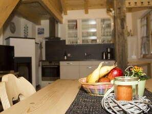 A wooden table with a woven placemat, a basket of fruit, a candle, and a glass jar.