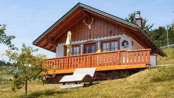 Eine Holz-Blockhütte mit Balkon, Schornstein und Dekoration mit Hirschgeweih.