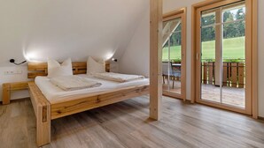 A bedroom with a wooden bed, a nightstand, and a large sliding glass door leading to an outdoor deck. - Apartment 'Falkennest' with Mountain View, Shared Garden and Wi-Fi (Wolfach)