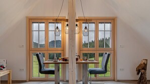 A dining area with a table, chairs, and a view of a green landscape through large windows. - Apartment 'Falkennest' with Mountain View, Shared Garden and Wi-Fi (Wolfach)