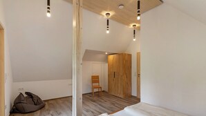 A bedroom with a loft bed, a wooden wardrobe, a chair, and a bean bag. - Apartment 'Falkennest' with Mountain View, Shared Garden and Wi-Fi (Wolfach)