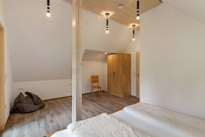 Un dormitorio con cama en literas, un armario de madera, una silla y un sillón de peluche.