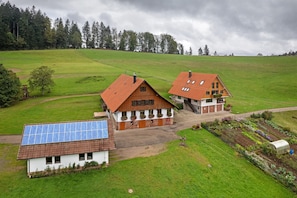 A rural house with a large garden, solar panels, and a greenhouse.
