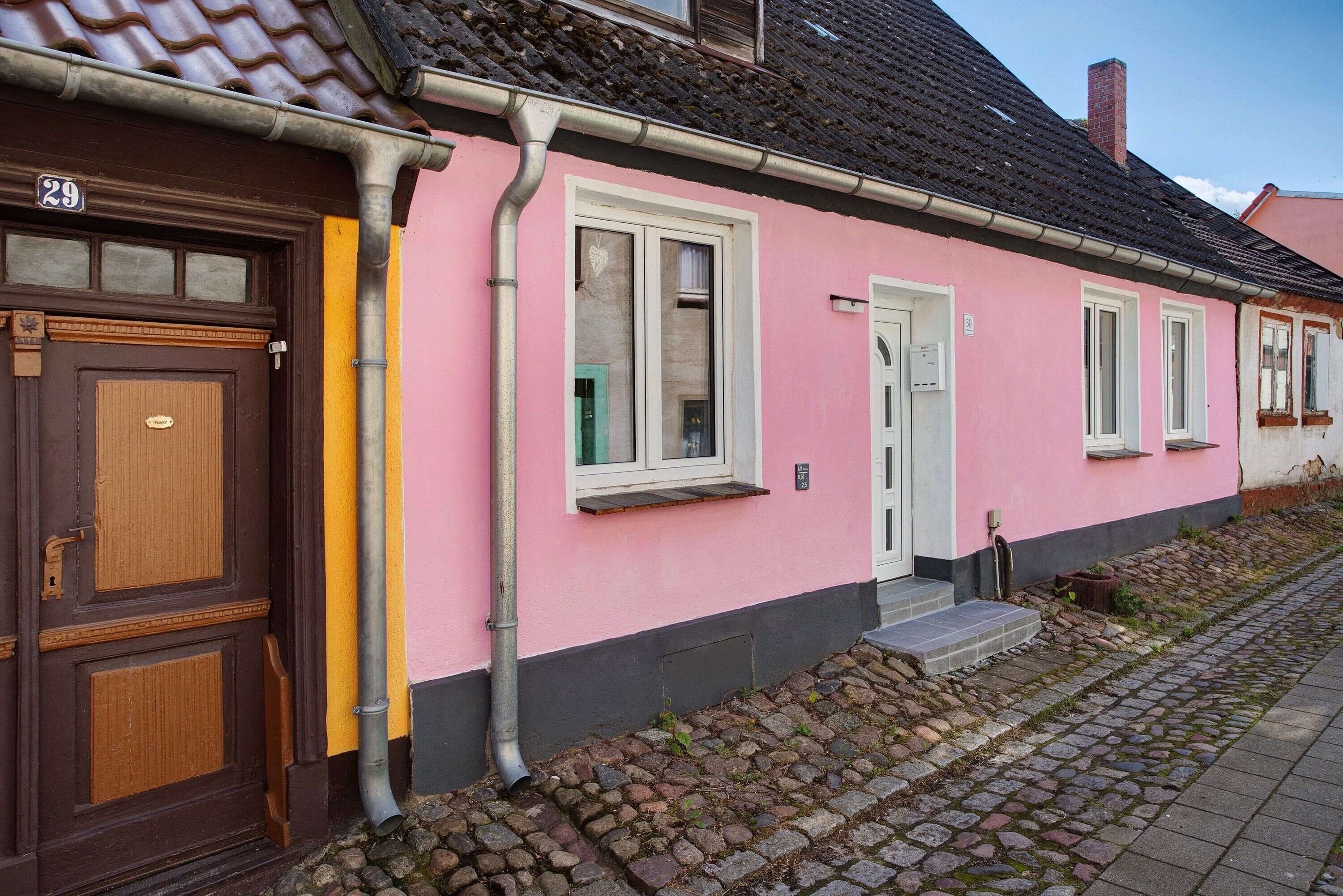 A pink building with a brown door, numbered 29, and a small porch with steps.