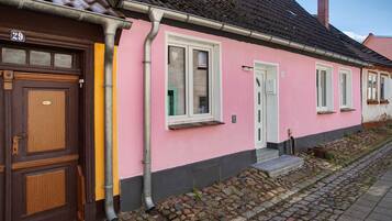 A pink building with a brown door, numbered 29, and a small porch with steps.
