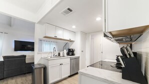 Una cucina moderna con mobili bianchi, lavastoviglie in acciaio inossidabile e forno integrato.