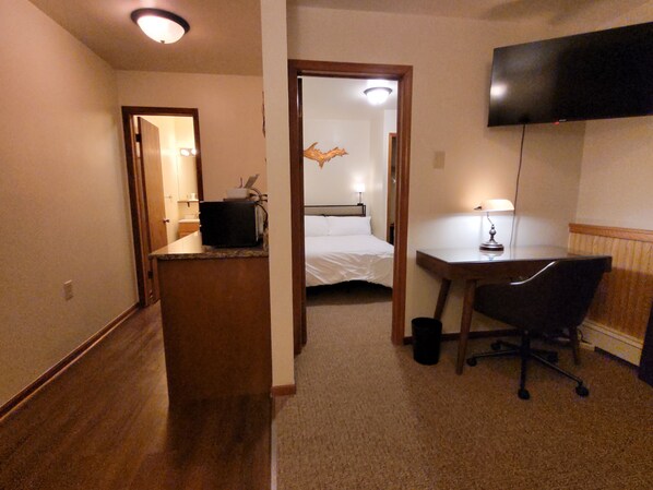 A hotel room with a bed, desk, chair, and a television mounted on the wall. - SIngle Executive Suite (Laurium)