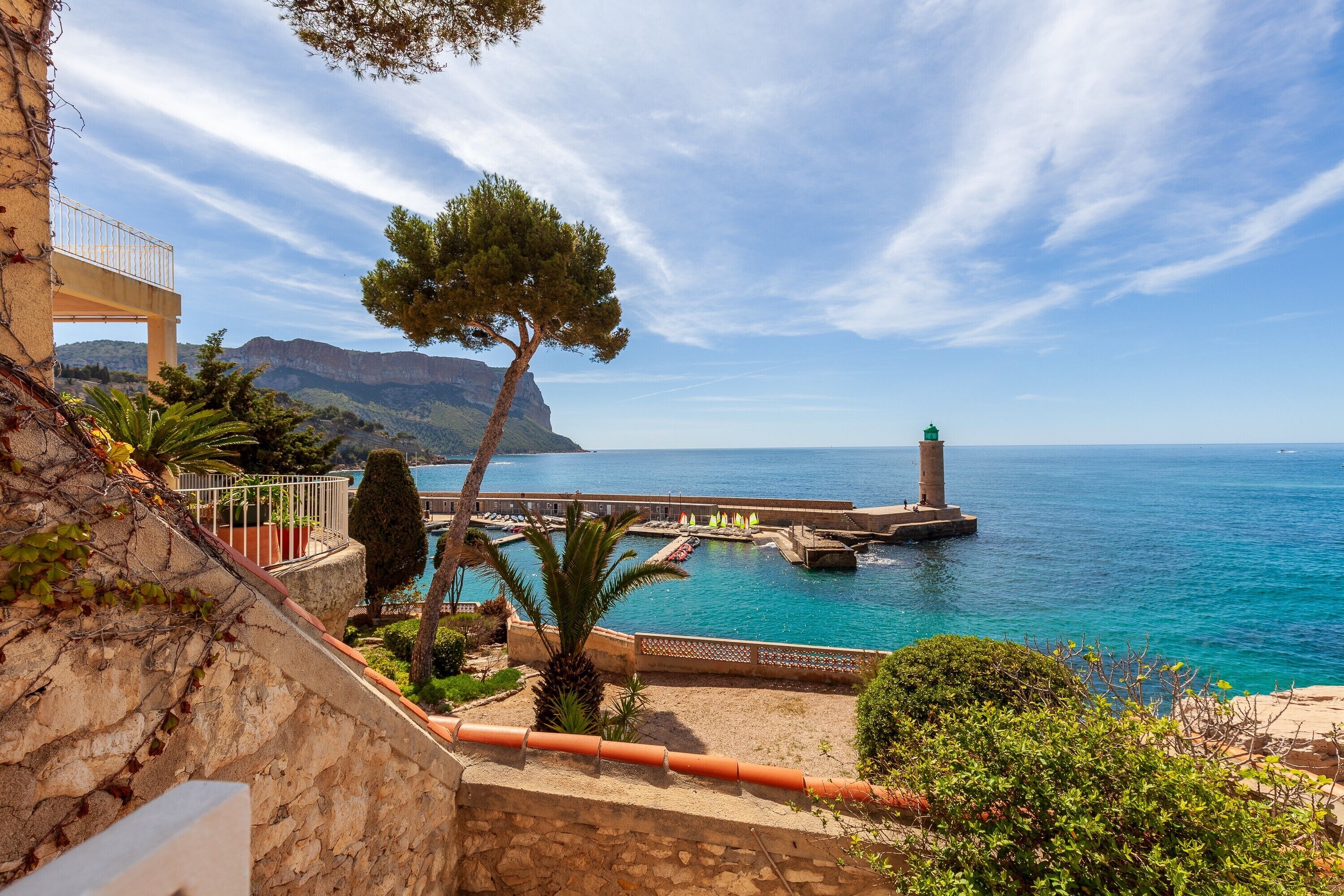 A coastal view with a lighthouse, stone walls, and a clear sky.