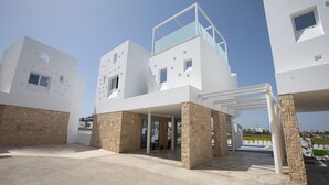 A modern two-story building with a flat roof, a balcony, and a covered entrance area.