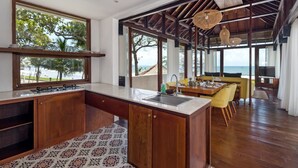 Een ruime keuken met een groot schiereiland, een eethoek met gele stoelen en uitzicht op zee.